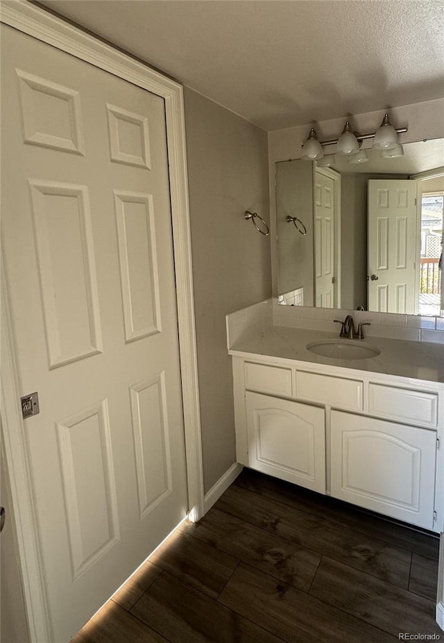 bathroom featuring a textured ceiling, wood finished floors, vanity, and baseboards