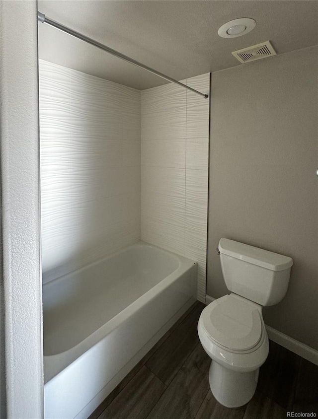 full bathroom with toilet, wood finished floors, visible vents, baseboards, and shower / washtub combination