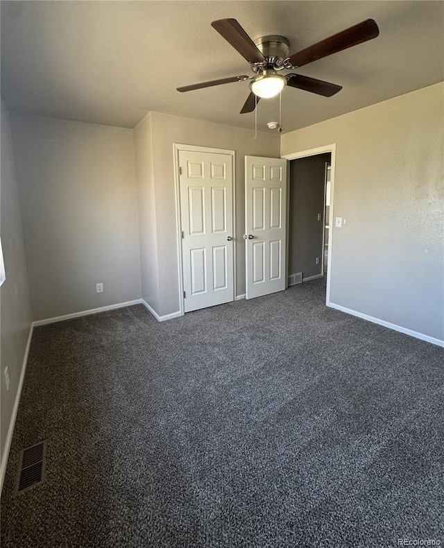 unfurnished bedroom with baseboards, visible vents, and dark colored carpet