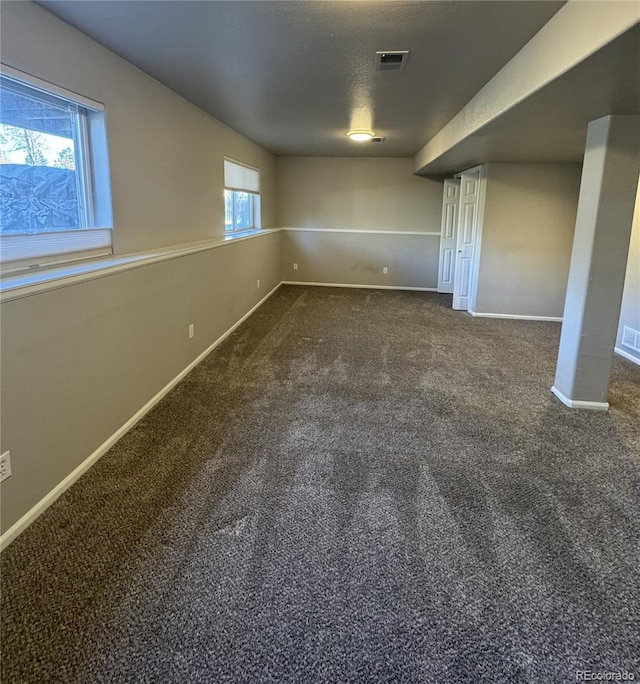 basement featuring baseboards, a textured ceiling, visible vents, and carpet flooring