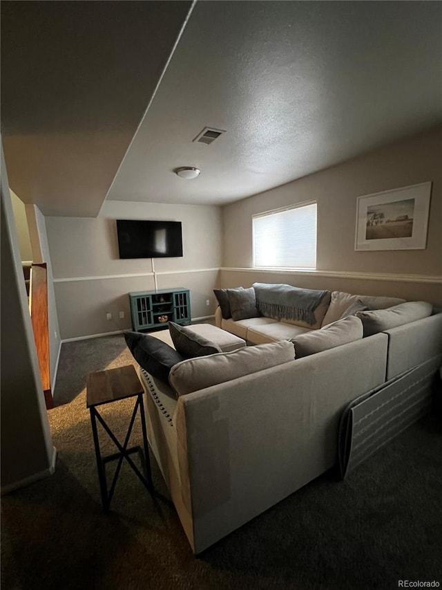 living area with dark colored carpet, visible vents, and baseboards