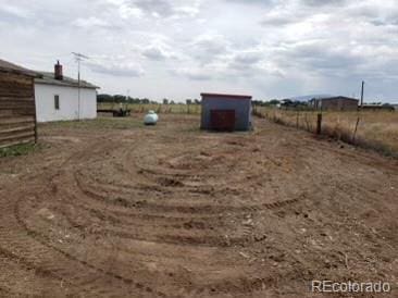 view of yard featuring a rural view, an outdoor structure, and a storage shed