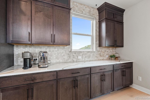 423 Rogers Way, Castle Rock, CO 80104 - kitchen featuring decorative backsplash, light wood finished floors, dark brown cabinets, and light stone countertops