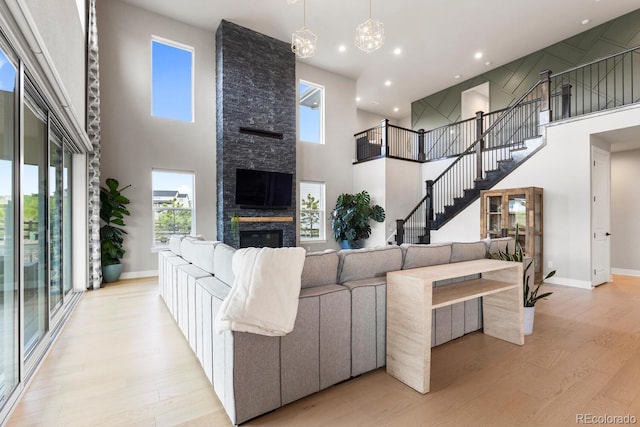 423 Rogers Way, Castle Rock, CO 80104 - living area with a high ceiling, light wood-type flooring, a stone fireplace, recessed lighting, and a chandelier