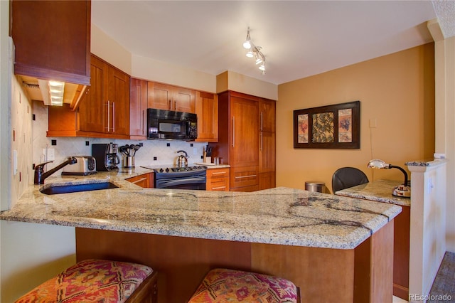 kitchen with kitchen peninsula, black appliances, and light stone countertops