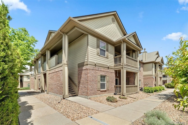 23346 E 5th Pl Unit 101, Aurora, CO 80018 - view of side of home with a balcony, brick siding, and stairway