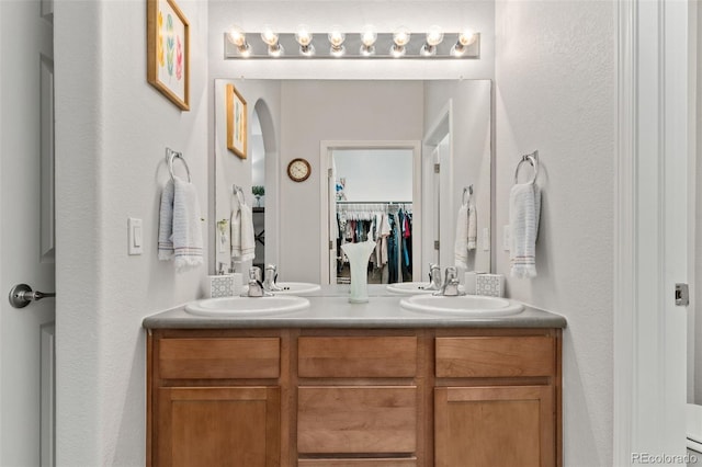 23346 E 5th Pl Unit 101, Aurora, CO 80018 - full bathroom featuring double vanity, a walk in closet, and a textured wall