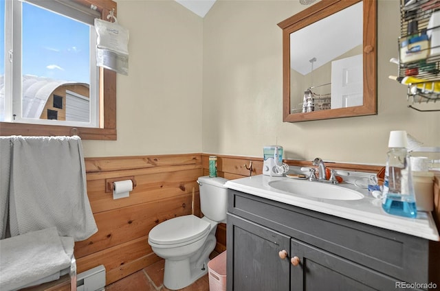 bathroom featuring toilet, vanity, a wainscoted wall, and a shower