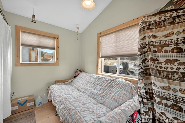 bedroom with multiple windows, vaulted ceiling, and wood finished floors