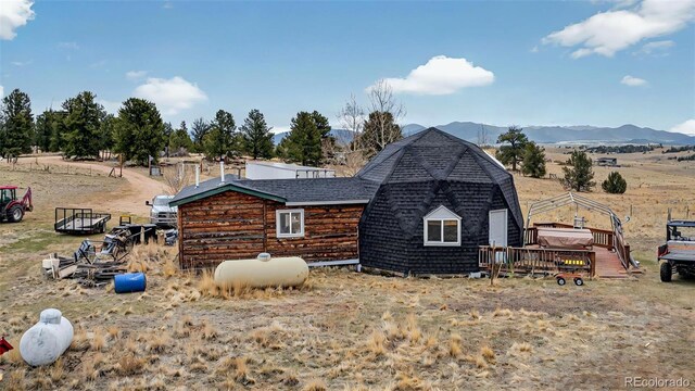 back of property featuring a deck with mountain view and roof with shingles