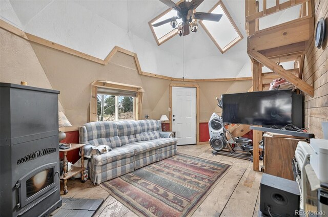 living area with a skylight, a ceiling fan, high vaulted ceiling, and light wood-type flooring