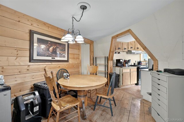 dining area featuring wood walls, light wood finished floors, and a chandelier