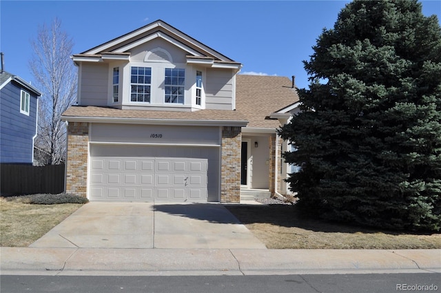 traditional-style house with brick siding, a shingled roof, fence, concrete driveway, and a garage