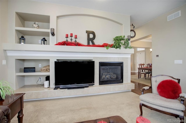 carpeted living room with built in shelves and a fireplace