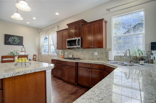 kitchen with appliances with stainless steel finishes, backsplash, dark wood-type flooring, sink, and pendant lighting