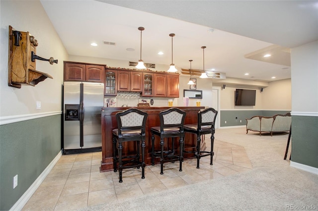 kitchen with light carpet, stainless steel fridge, a breakfast bar, and hanging light fixtures