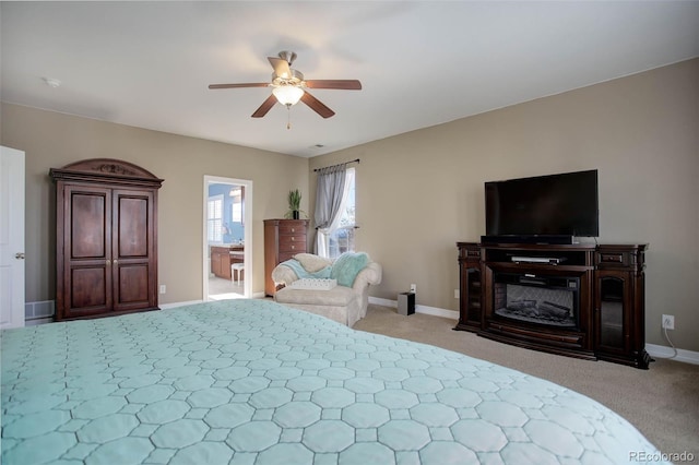 bedroom featuring ceiling fan, light colored carpet, and connected bathroom