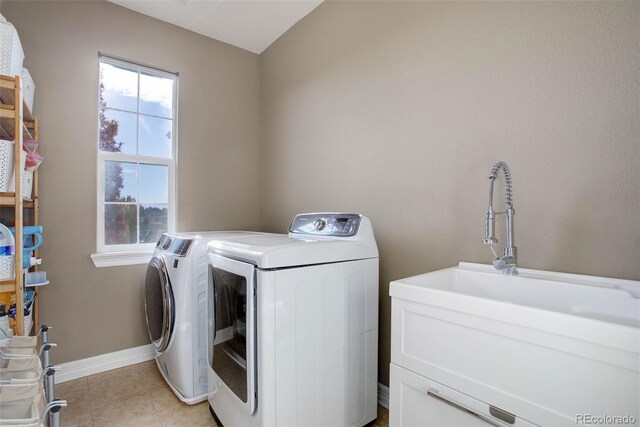 clothes washing area featuring washer and dryer, light tile patterned flooring, cabinets, and sink