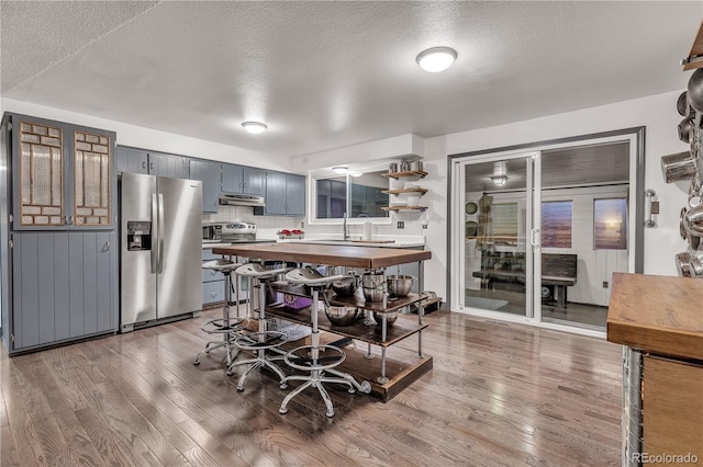 kitchen featuring hardwood / wood-style floors, sink, decorative backsplash, a textured ceiling, and stainless steel appliances