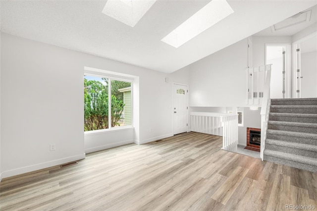 2777 S Sedalia St, Aurora, CO 80013 - unfurnished living room featuring a skylight, wood finished floors, vaulted ceiling, stairs, and a fireplace