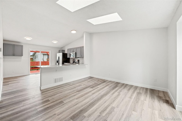 2777 S Sedalia St, Aurora, CO 80013 - unfurnished living room with a skylight, light wood-type flooring, and lofted ceiling