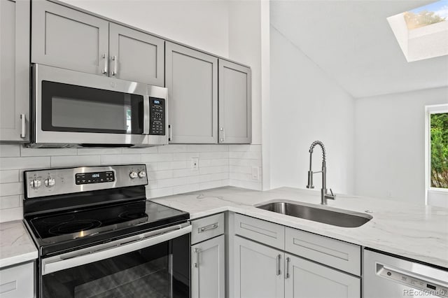 2777 S Sedalia St, Aurora, CO 80013 - kitchen featuring appliances with stainless steel finishes, a skylight, gray cabinetry, vaulted ceiling, and decorative backsplash