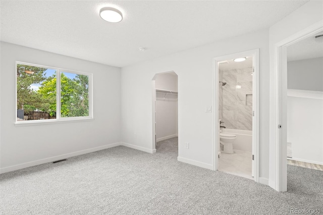 2777 S Sedalia St, Aurora, CO 80013 - unfurnished bedroom featuring a walk in closet, carpet flooring, arched walkways, a closet, and ensuite bath