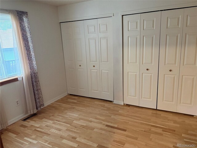14963 E Adriatic Pl, Aurora, CO 80014 - unfurnished bedroom featuring two closets and light wood-style flooring