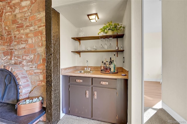 bar featuring brick wall, gray cabinets, and sink