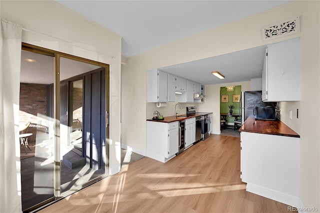 kitchen featuring white cabinetry, sink, light hardwood / wood-style flooring, and stainless steel appliances