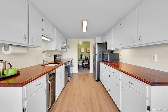 kitchen with stainless steel appliances, white cabinetry, sink, and wine cooler