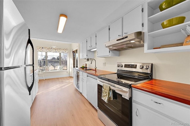 kitchen with sink, white cabinetry, light wood-type flooring, appliances with stainless steel finishes, and pendant lighting