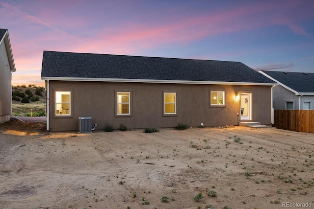 back house at dusk featuring cooling unit