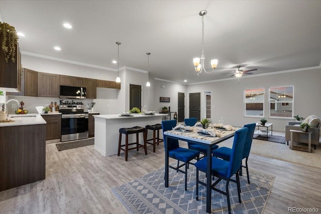 dining space with ceiling fan, ornamental molding, sink, and light wood-type flooring