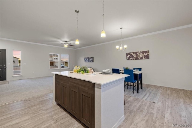 kitchen featuring crown molding, decorative light fixtures, a center island, and light wood-type flooring