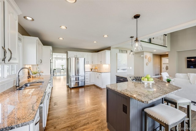 7067 Gray Fox Ct, Highlands Ranch, CO 80130 - kitchen featuring stainless steel appliances, a sink, light wood-style floors, tasteful backsplash, and a kitchen bar