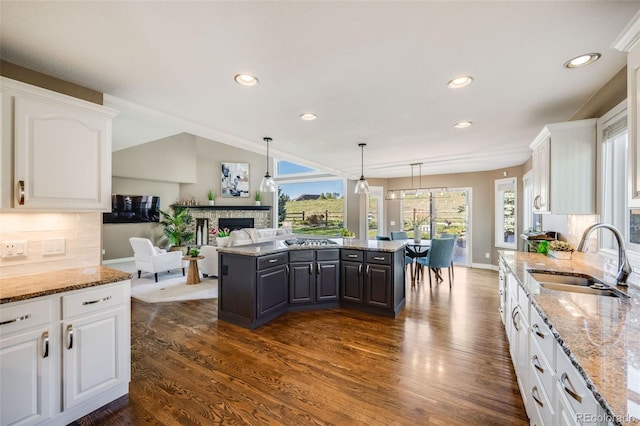 7067 Gray Fox Ct, Highlands Ranch, CO 80130 - kitchen with a sink, a fireplace, a center island, white cabinetry, and recessed lighting