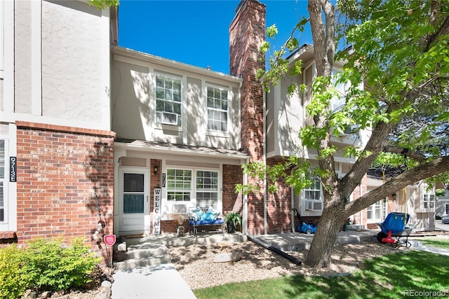 9713 W Chatfield Ave Unit F, Littleton, CO 80128 - view of front facade featuring brick siding, stucco siding, and a chimney
