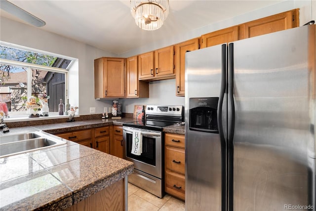 9713 W Chatfield Ave Unit F, Littleton, CO 80128 - kitchen featuring stainless steel appliances, tile counters, a sink, light tile patterned floors, and brown cabinets