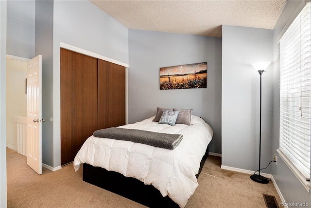 9713 W Chatfield Ave Unit F, Littleton, CO 80128 - bedroom with light colored carpet, a closet, multiple windows, baseboards, and a textured ceiling