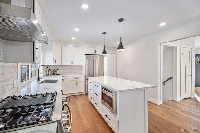 kitchen featuring wall chimney exhaust hood, stainless steel appliances, a center island, and white cabinets