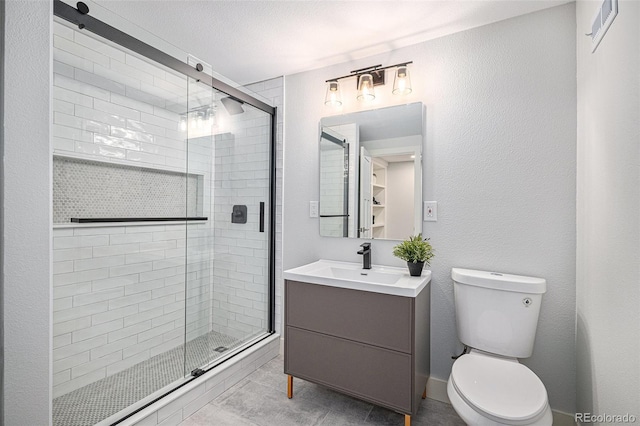 bathroom featuring vanity, a shower with shower door, and toilet