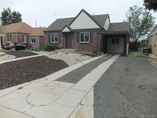 3243 Albion St, Denver, CO 80207 - tudor home featuring driveway, brick siding, a carport, and roof with shingles