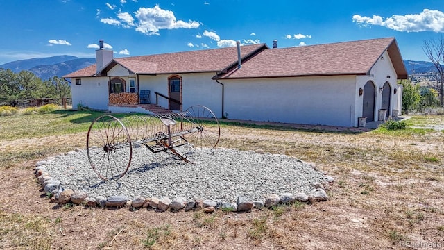 rear view of property with a mountain view, a yard, and a garage