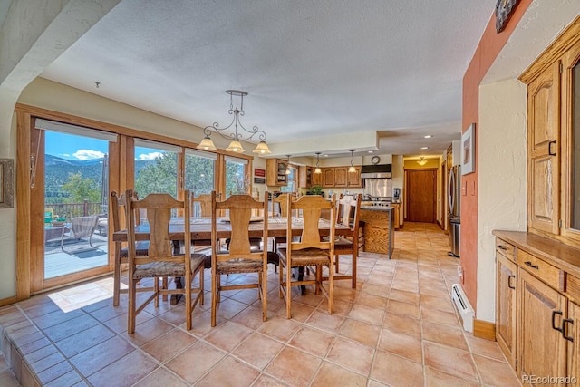 tiled dining space featuring a mountain view, a textured ceiling, a chandelier, and a baseboard radiator