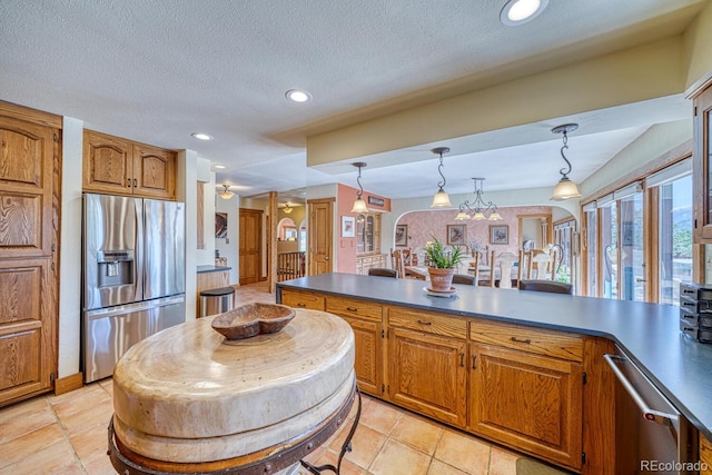 kitchen featuring a textured ceiling, decorative light fixtures, light tile patterned floors, and stainless steel appliances