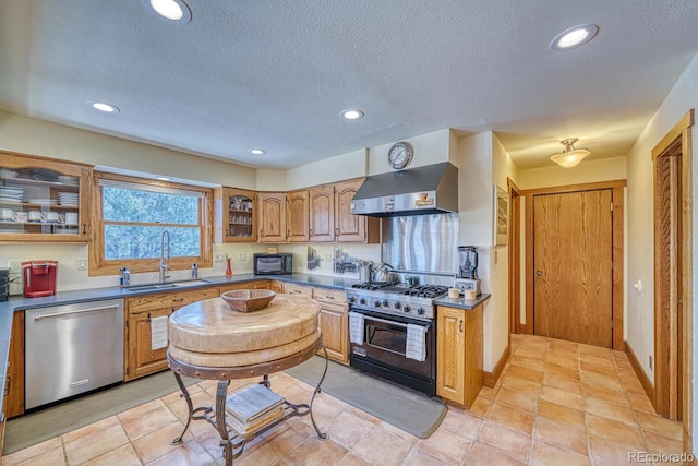 kitchen with a textured ceiling, wall chimney range hood, sink, light tile patterned floors, and black appliances