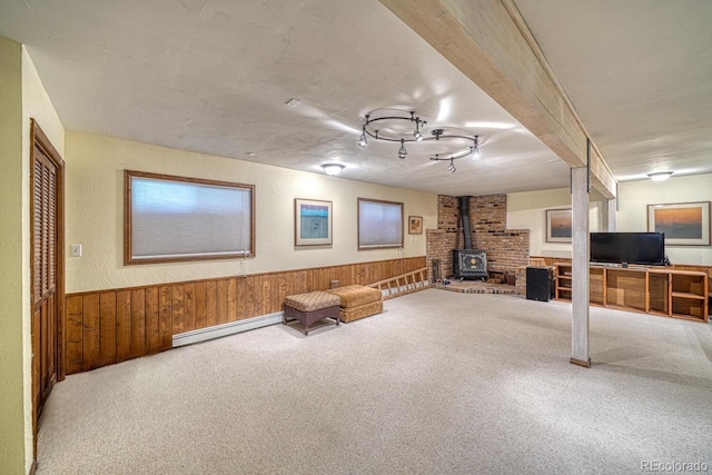 interior space featuring carpet flooring, wood walls, a wood stove, and baseboard heating