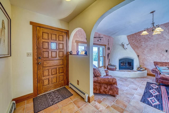 entryway featuring a wood stove, a chandelier, and a baseboard heating unit