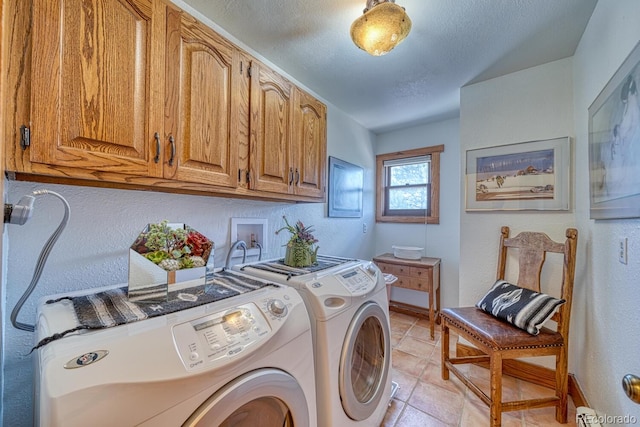 clothes washing area with washer and dryer, light tile patterned floors, a textured ceiling, and cabinets